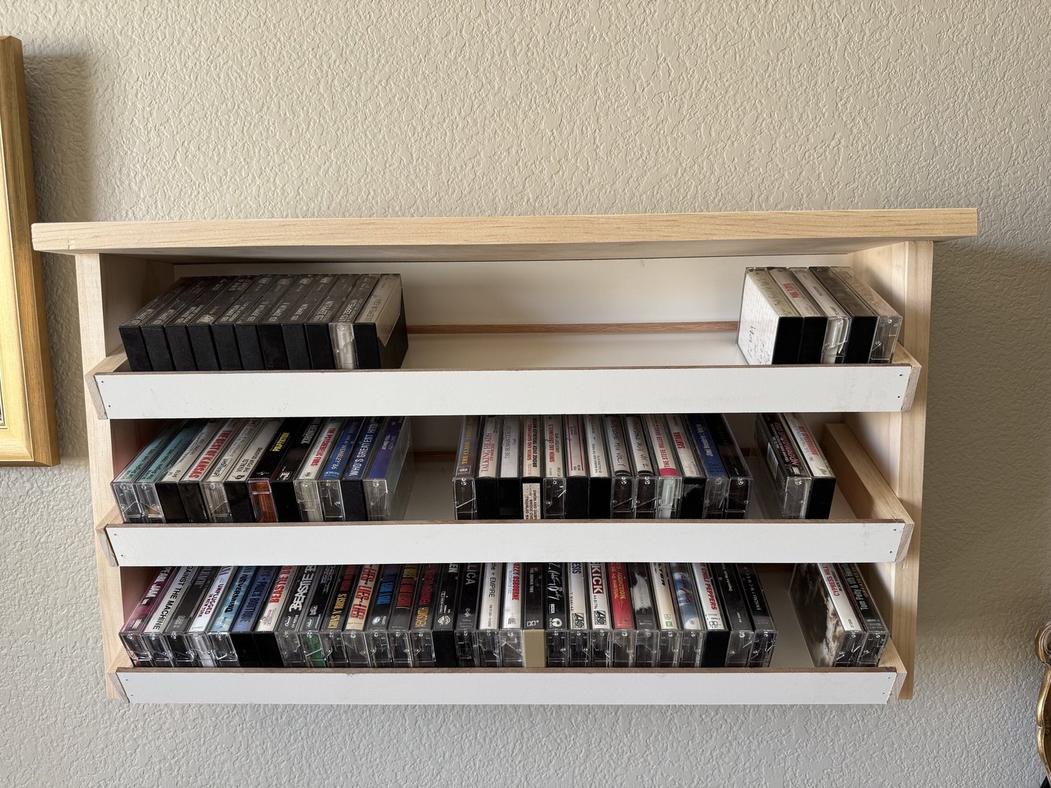 Finished wall-mounted cassette shelf holding more than 100 tapes
