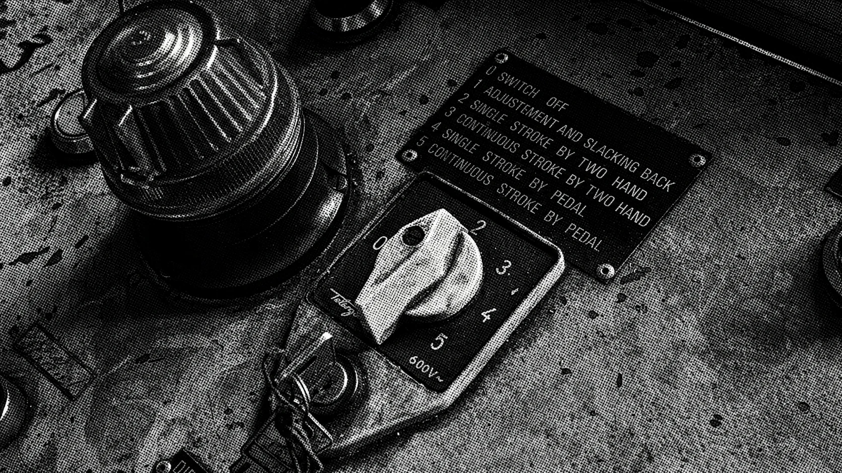 Worn industrial control panel with a numbered yellow selector, keyed switch, and large red warning light