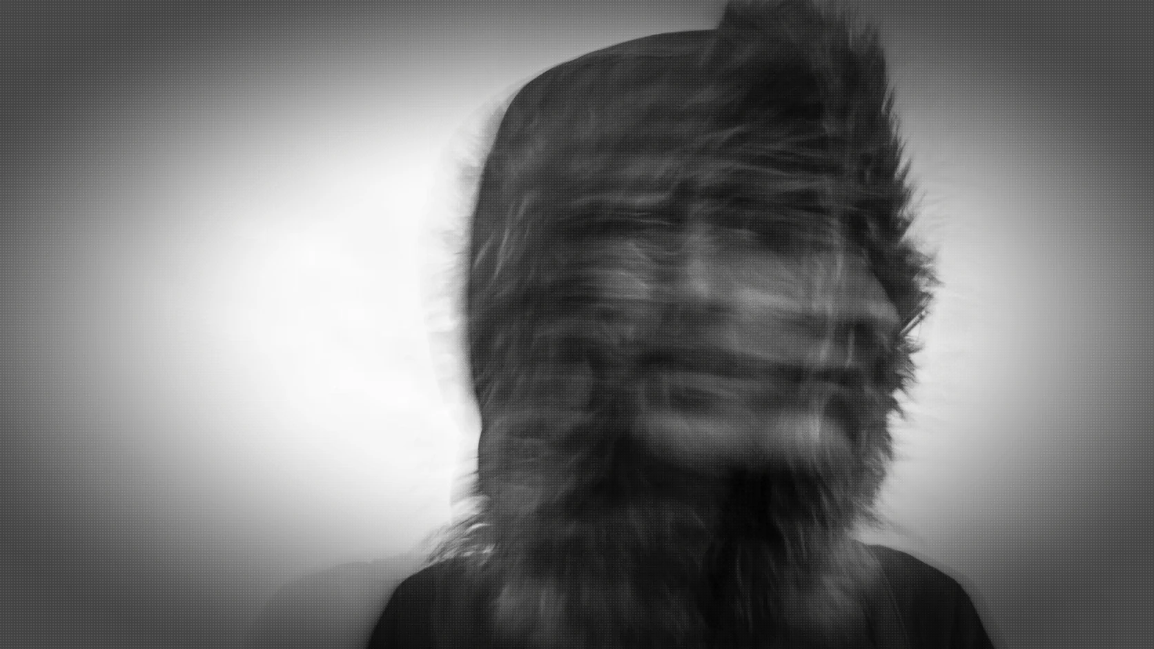 A blurred multiple-exposure portrait in which a person’s face appears to shift out of alignment